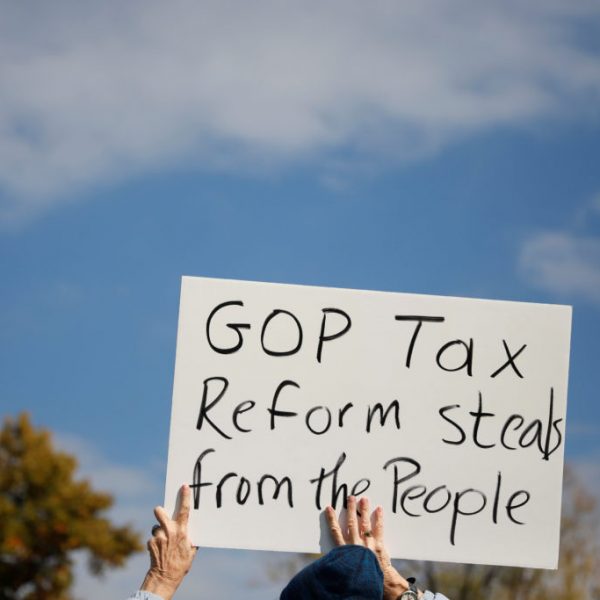 A demonstrator holds a sign during a rally against the Republican tax bill on Capitol Hill in Washington